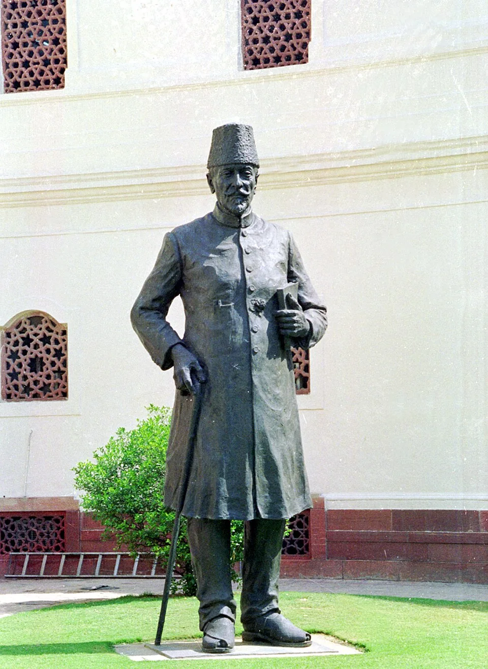 Bronze statue of Maulana Abul Kalam Azad standing with a walking stick and holding a book, in the Parliament complex, New Delhi.